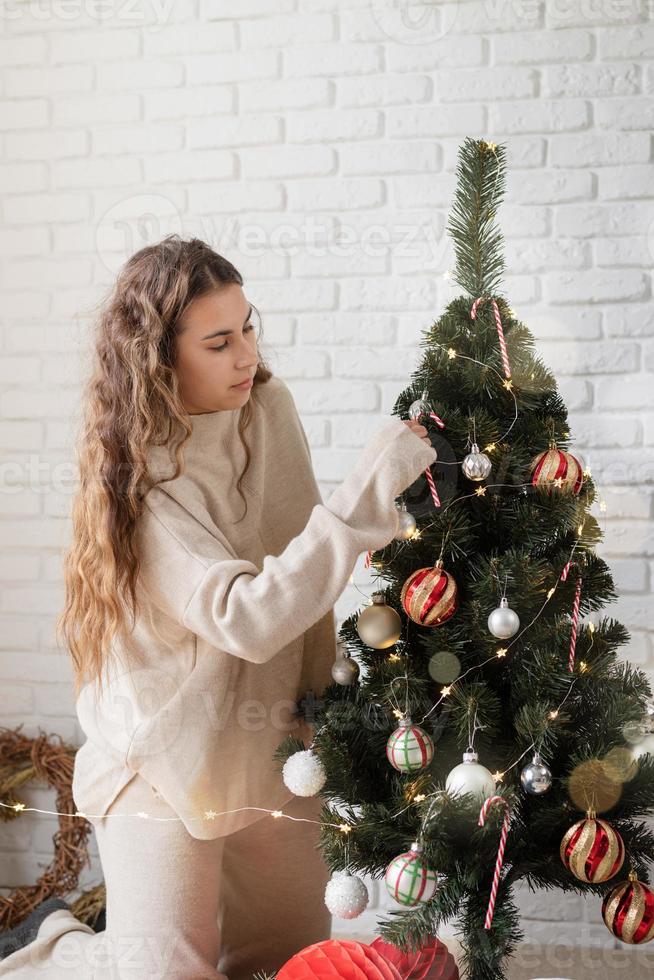Atractiva mujer joven decorar el árbol de navidad con luces de colores foto