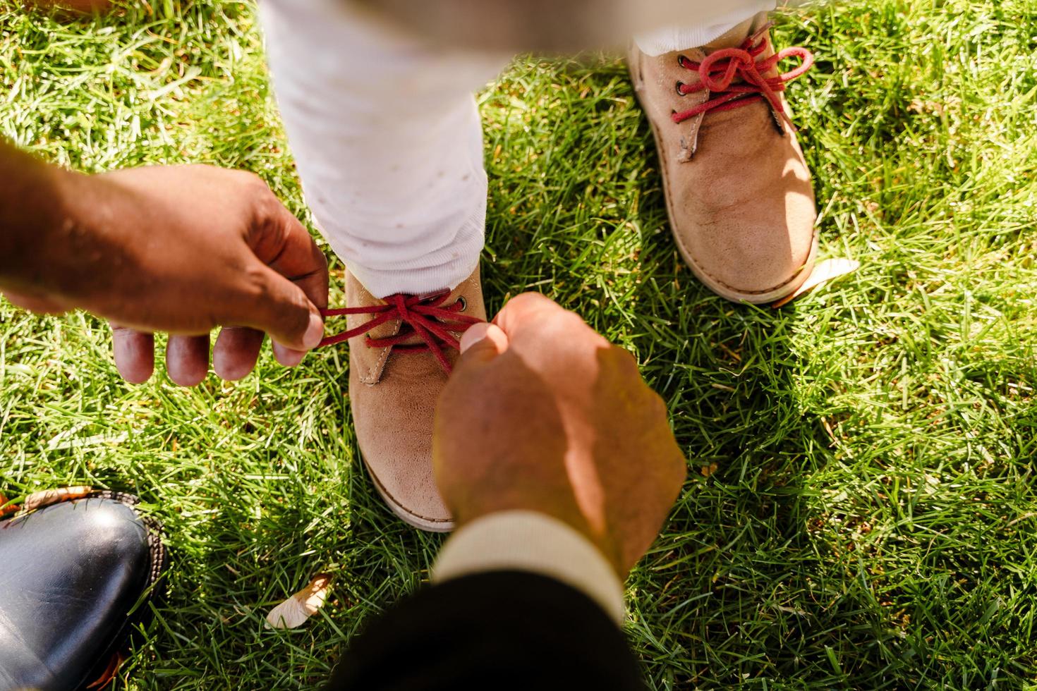 Black grandfather tying granddaughter's shoelaces while walking in autumn park photo