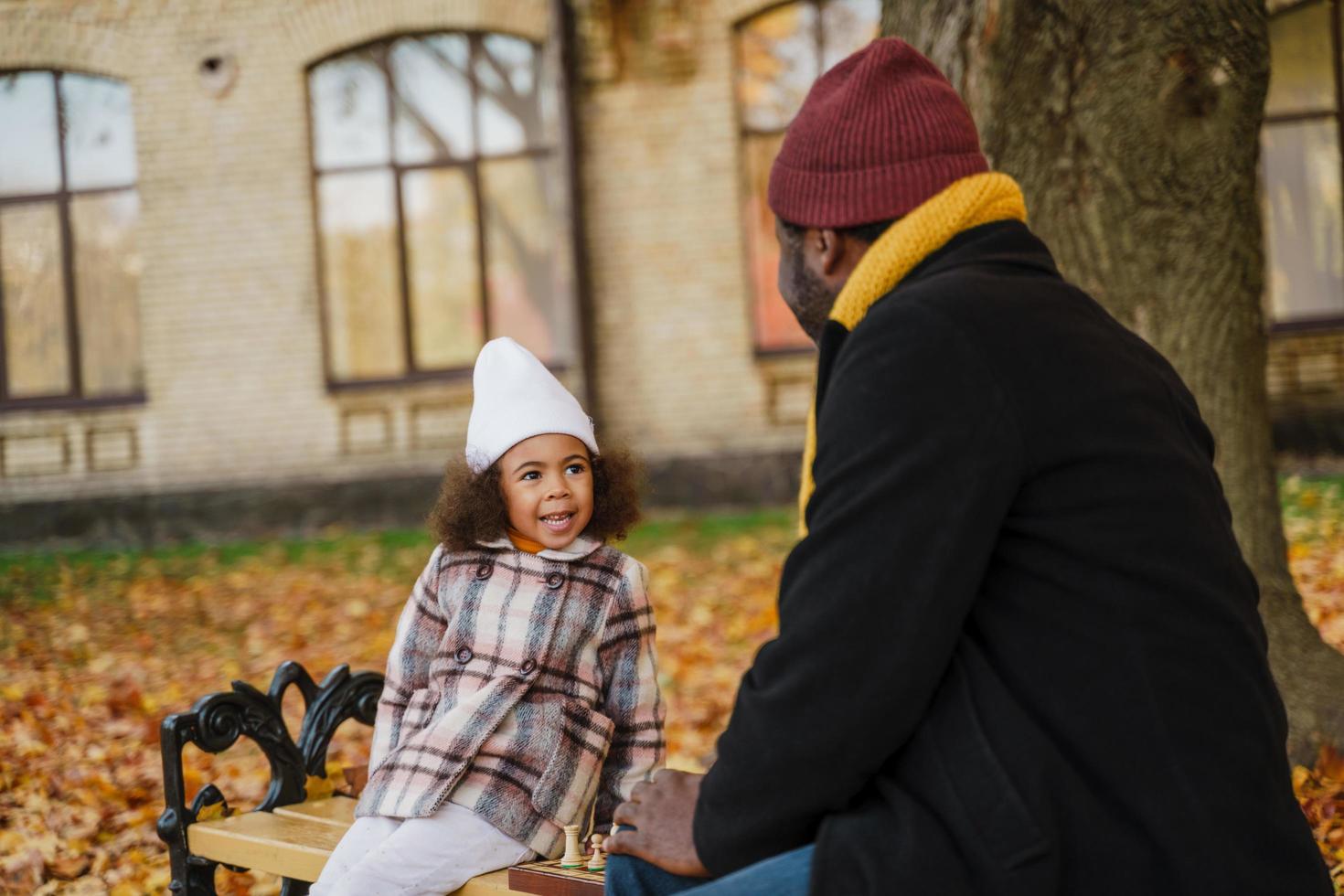 Abuelo y nieta negros jugando al ajedrez en el parque de otoño foto