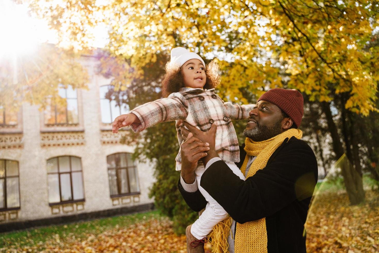 Black grandfather and granddaughter having fun while playing together in autumn park photo