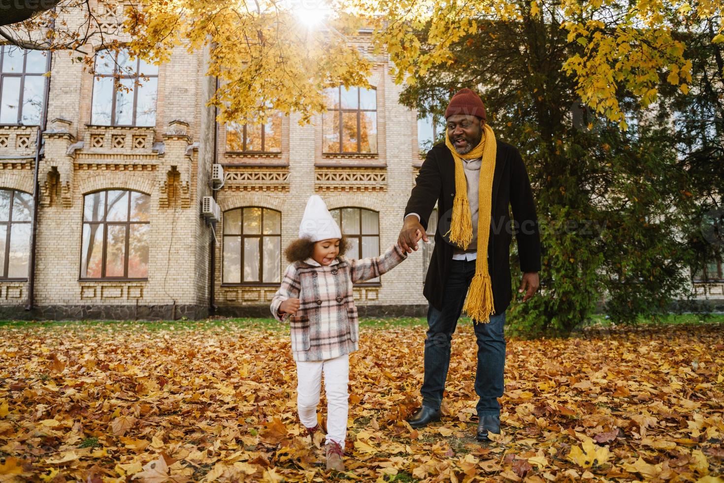 Abuelo y nieta negros divirtiéndose mientras juegan juntos en el parque de otoño foto