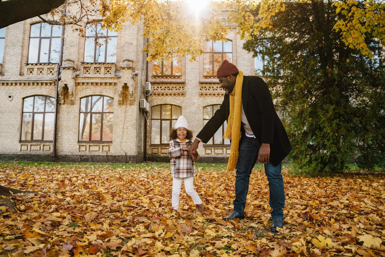 Abuelo y nieta negros divirtiéndose mientras juegan juntos en el parque de otoño foto