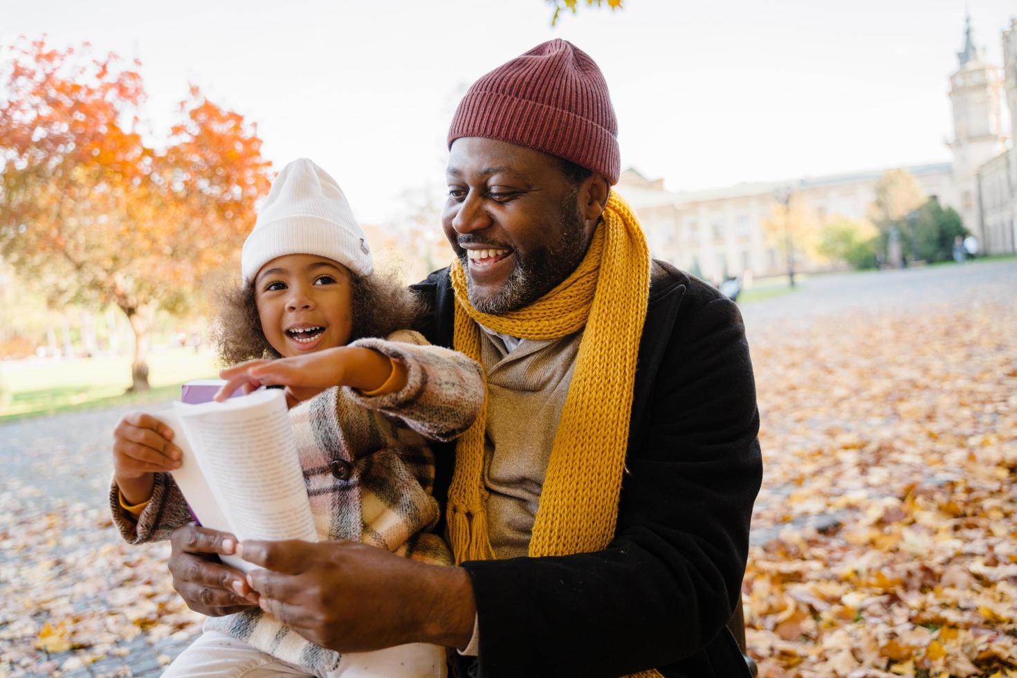 Libro de lectura de abuelo y nieta negro durante la caminata en el parque de otoño foto