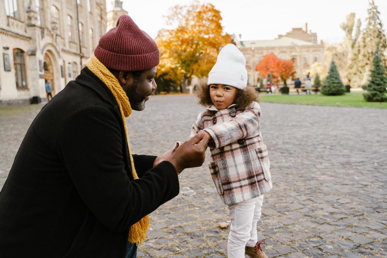 Black grandfather talking with his granddaughter and walking outdoors photo