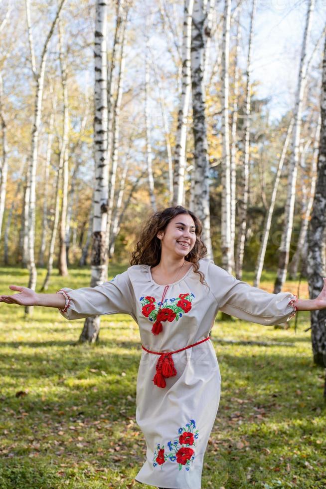 beautiful woman in ukrainian national traditional costume clothes dancing in forest photo