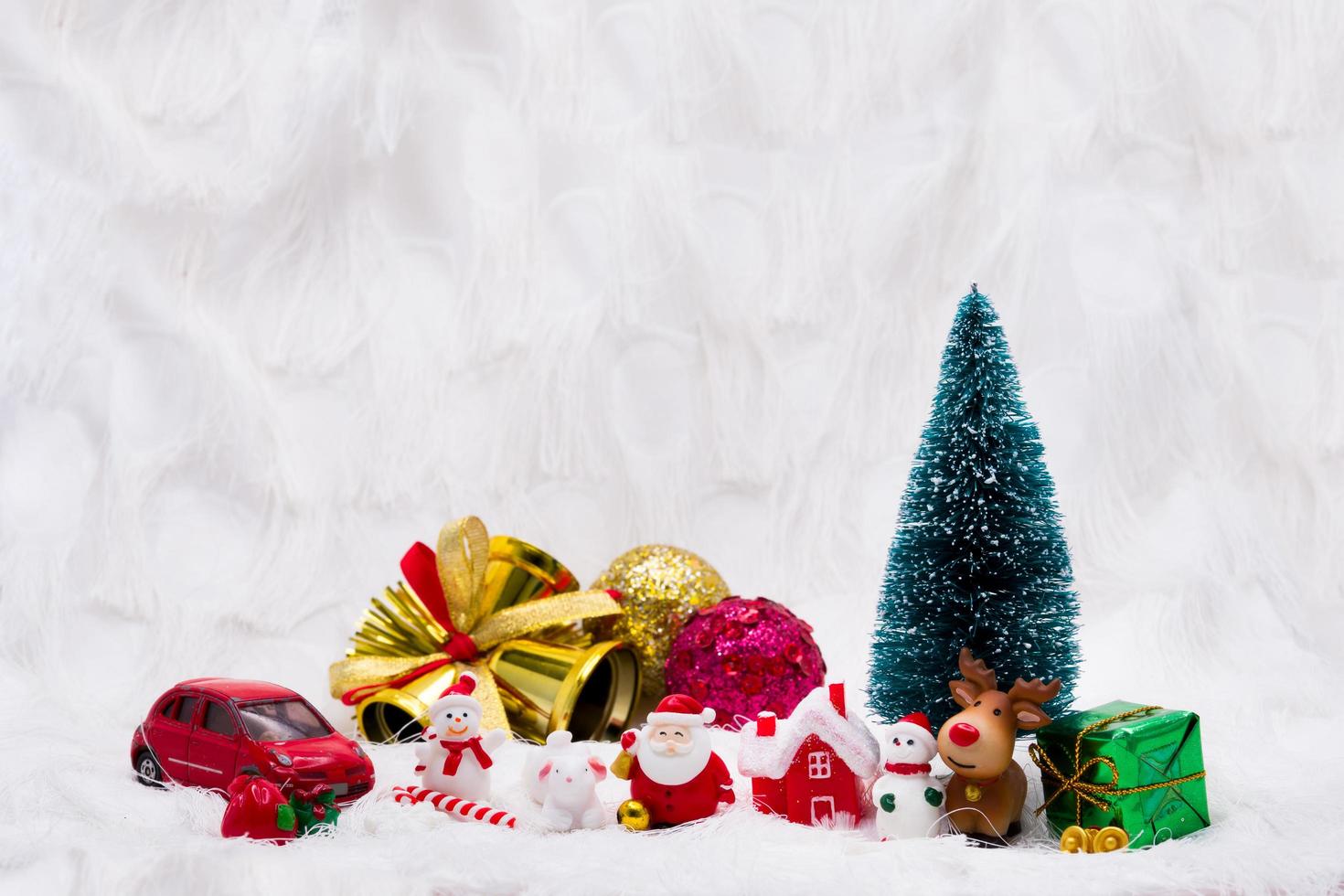 Merry Christmas and Happy New Year ceramic or  resin doll. Soft white background. Christmas tree, gold bells, red house, green gift box, brown reindeer,  two snowman, santa clause, red car, Candy Cane photo