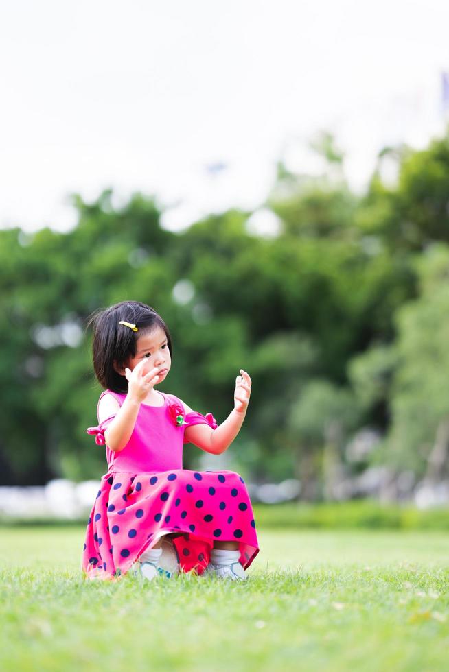 Vertical image. A young girl is stumped alone after losing a soccer match, a child sits on a soccer ball in the middle of a green lawn. photo