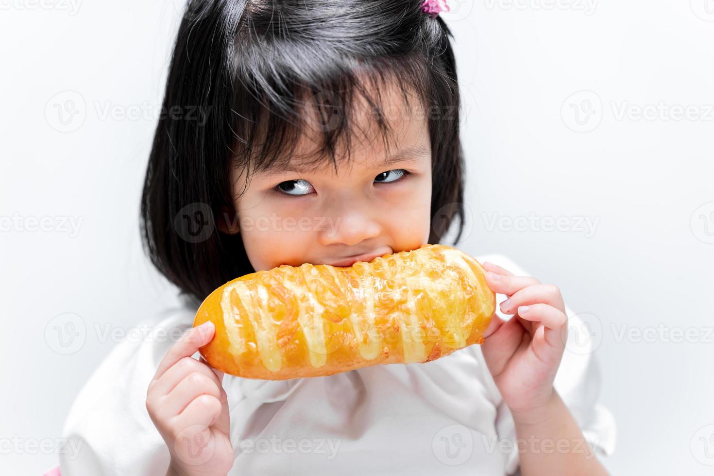 A 4 year old child was hungry, she ate the golden yellow bread with gusto. photo