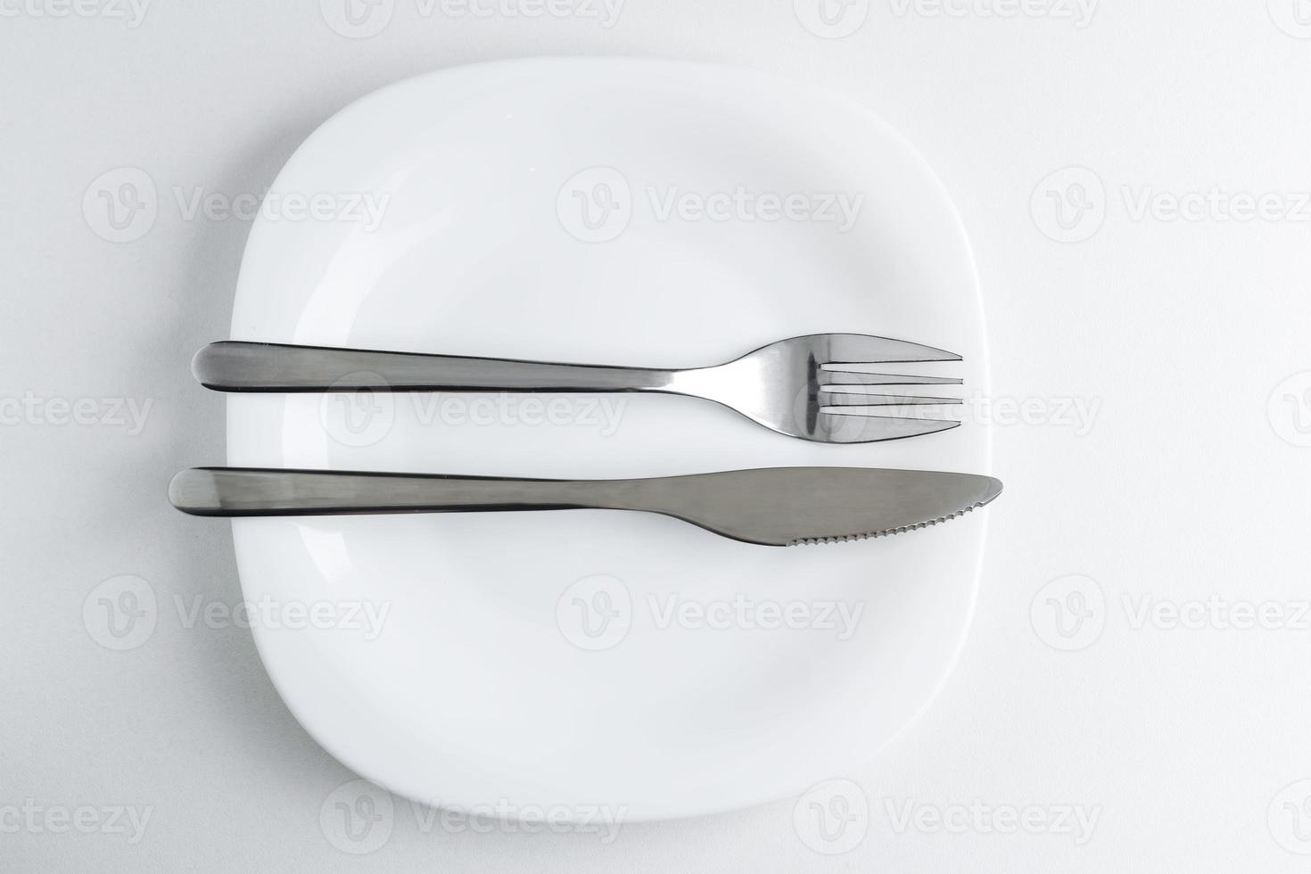 el tenedor y el cuchillo se encuentran en un plato blanco sobre un fondo claro. foto