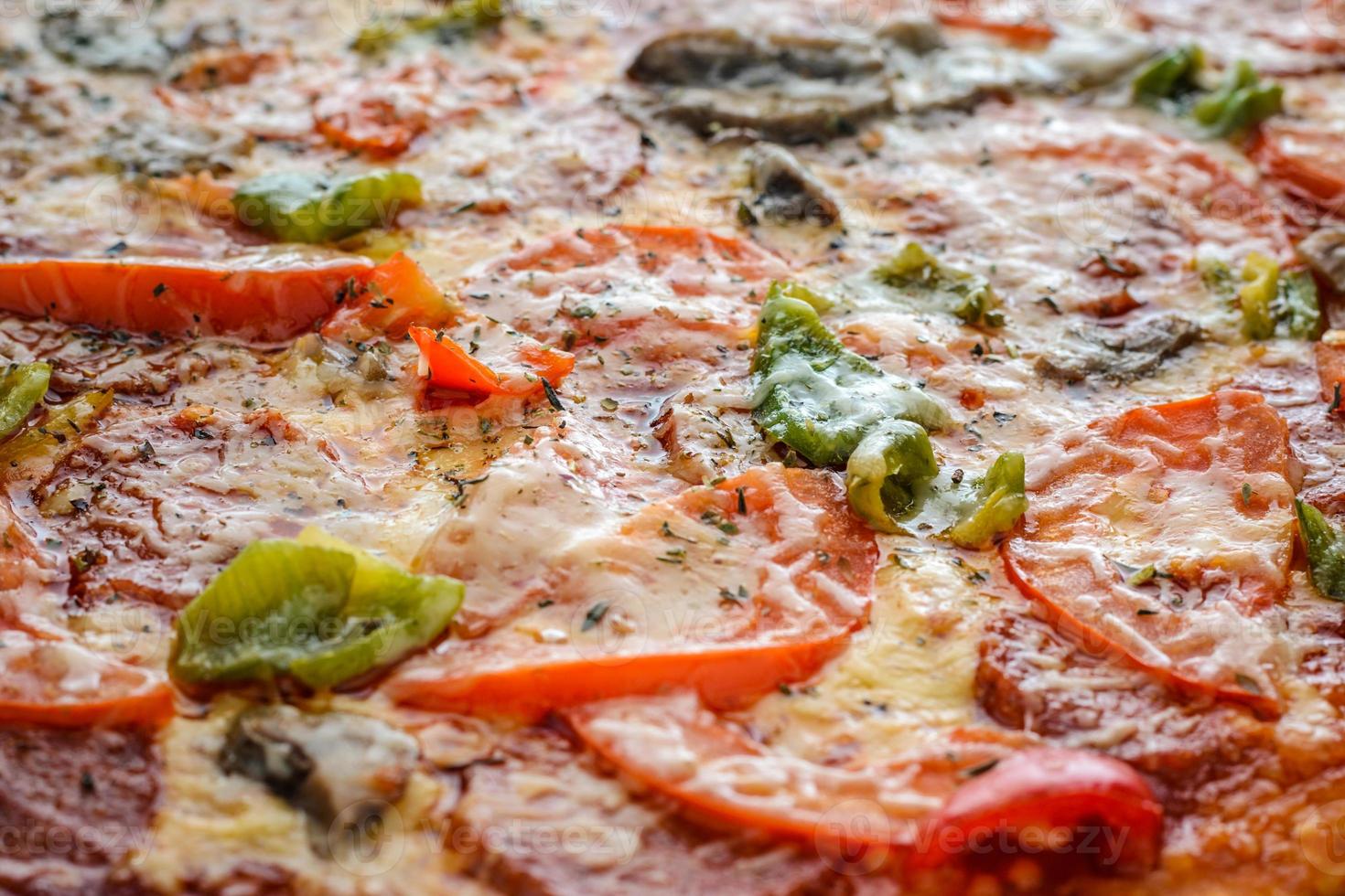 pizza con salami, tomates, pimiento y champiñones como fondo. lleno de marco de pizza foto