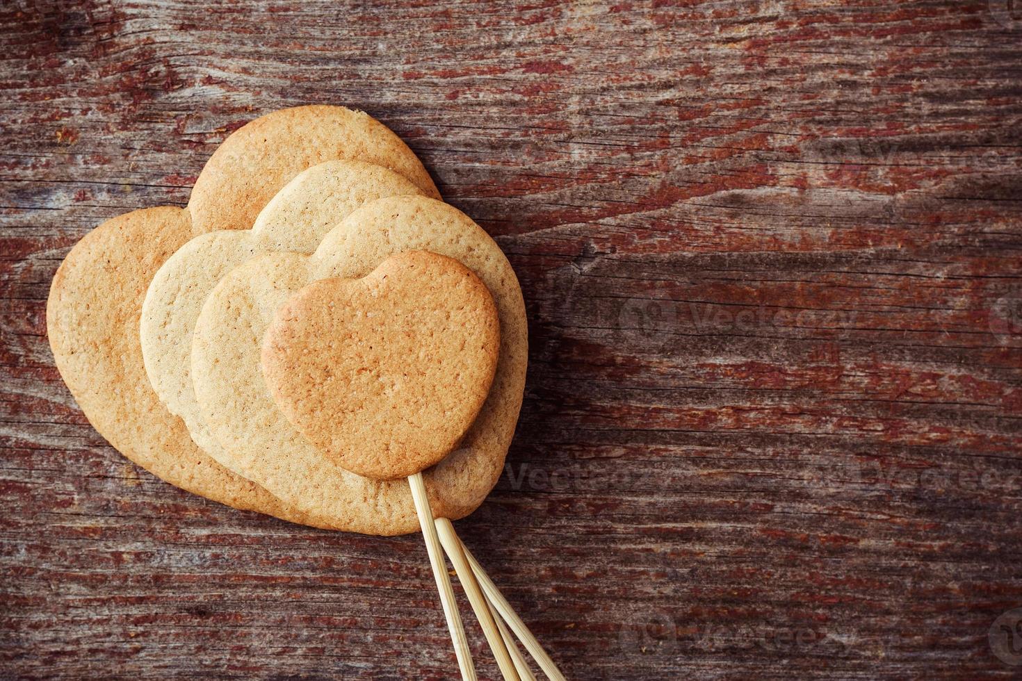 Galletas de jengibre en un palo en forma de corazones sobre un fondo de madera. vista superior foto