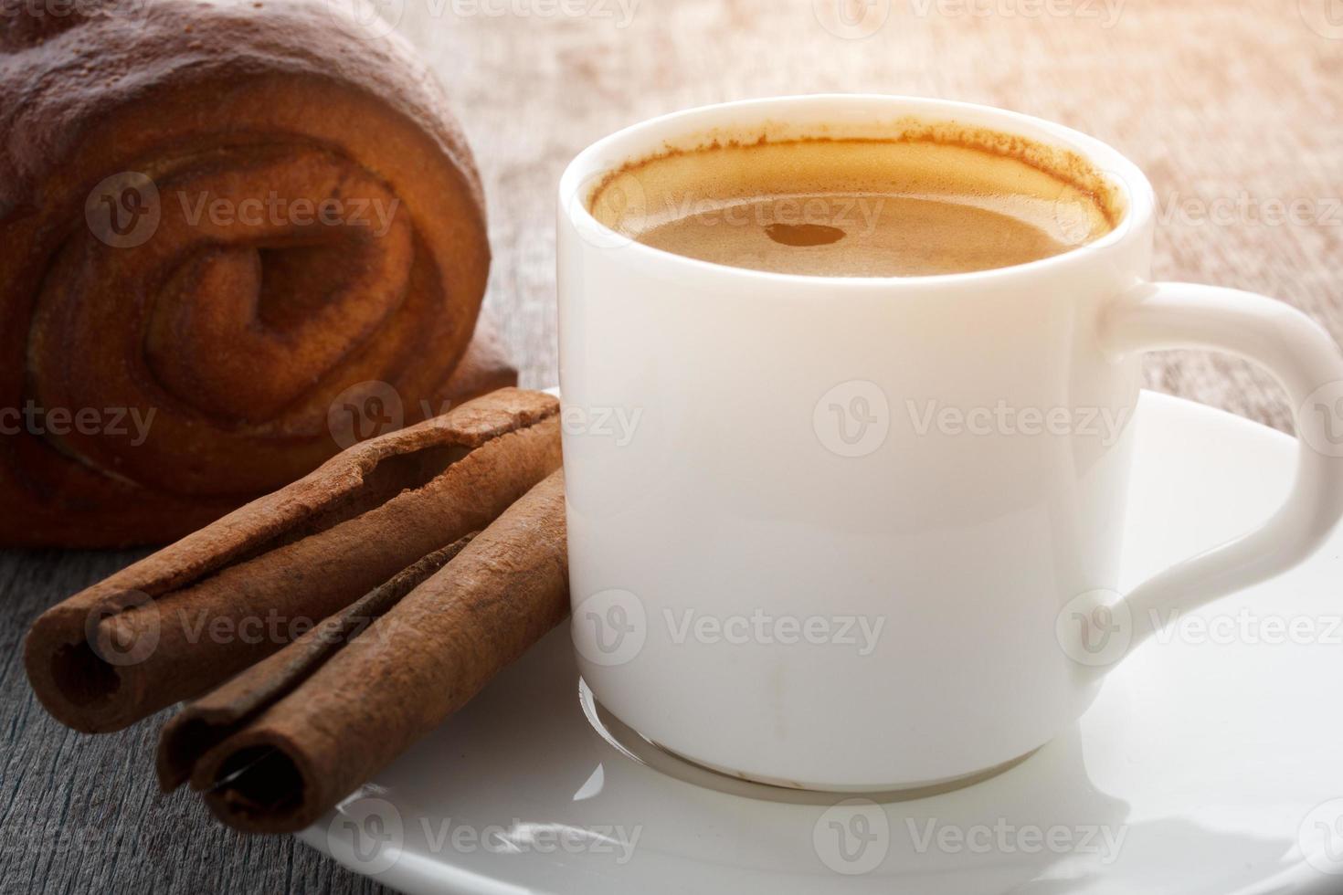 una taza de café aromático en un plato blanco sobre un fondo de madera. foto