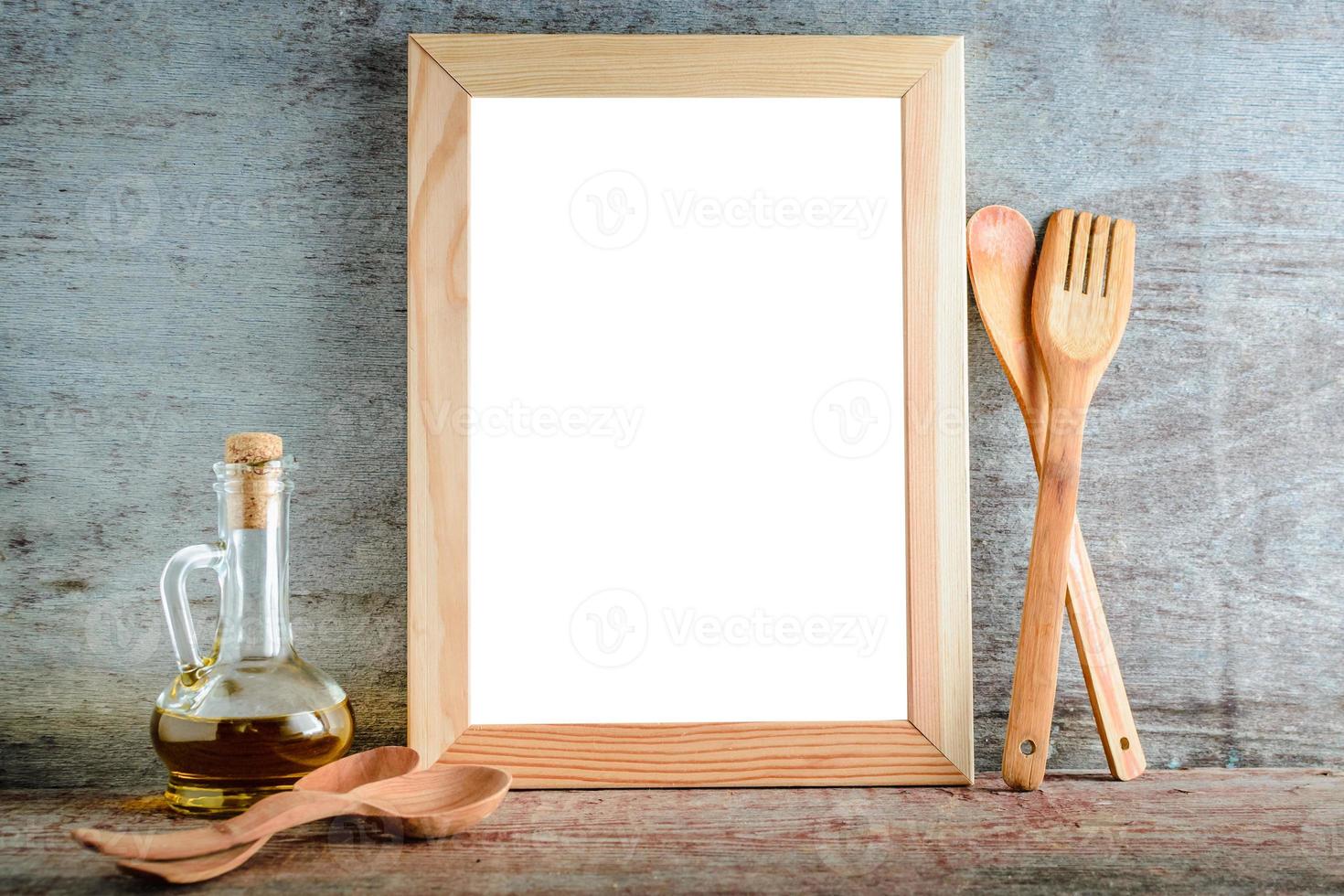 Bastidor de madera vacía con fondo blanco aislado y utensilios de cocina sobre un fondo de madera foto