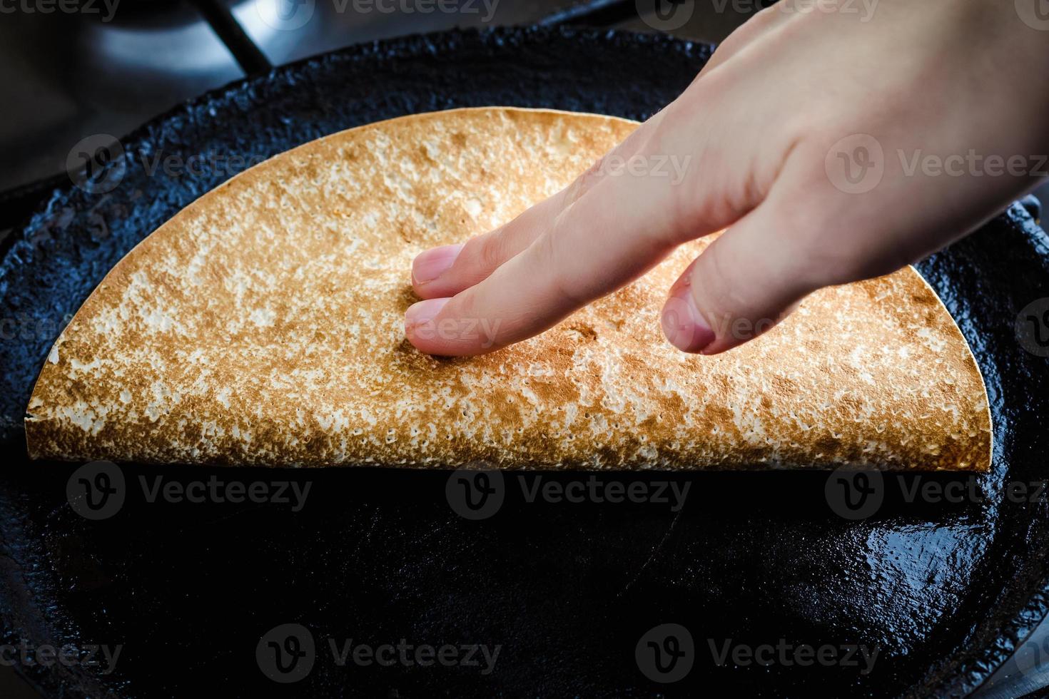 Mujer joven freír quesadilla en una sartén foto