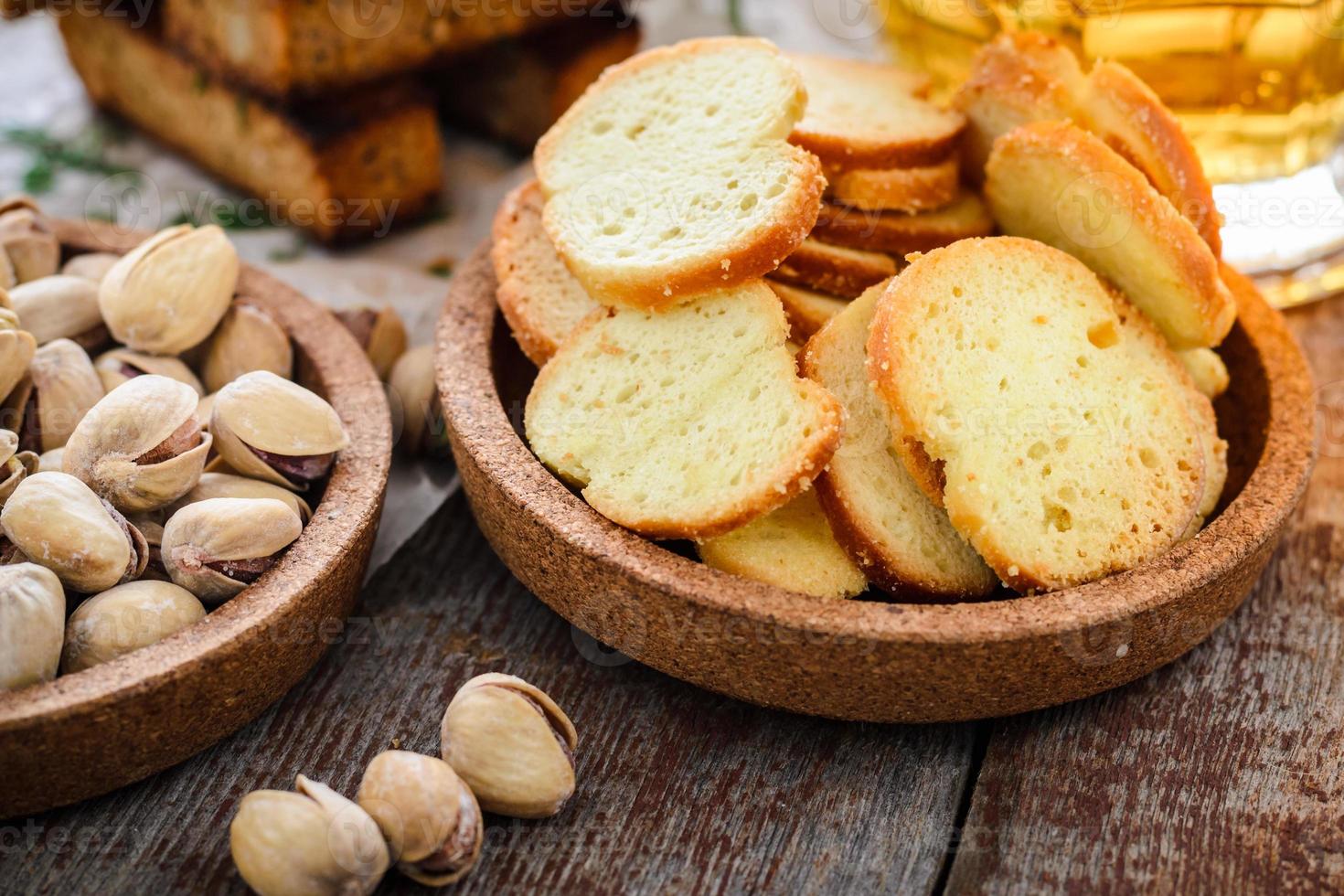 Snacks to beer, crackers, pistachios and a glass of light beer on a wooden table. photo