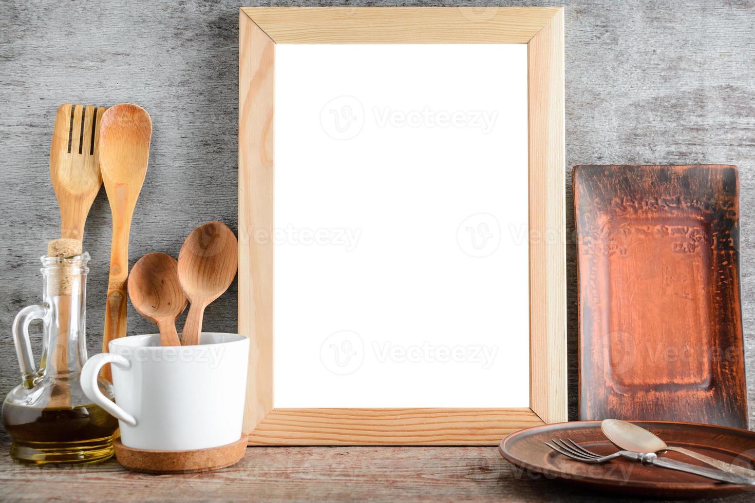 Empty wooden frame and kitchen accessories on the table photo