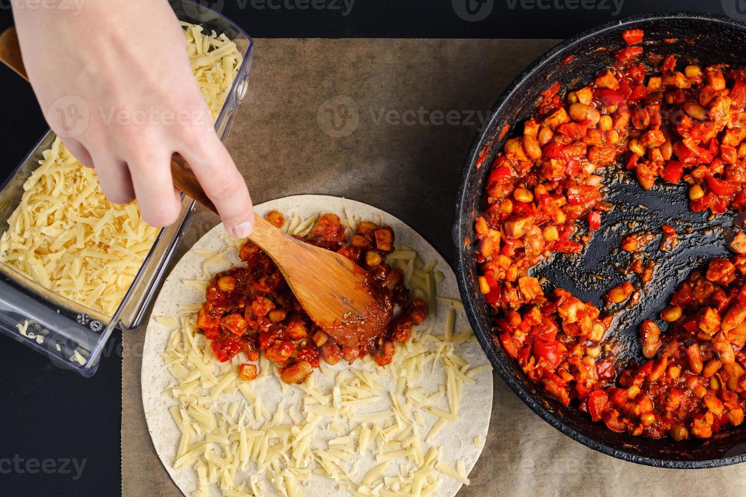 Making of quesadilla, a woman spreads a stuffing from a frying pan on a