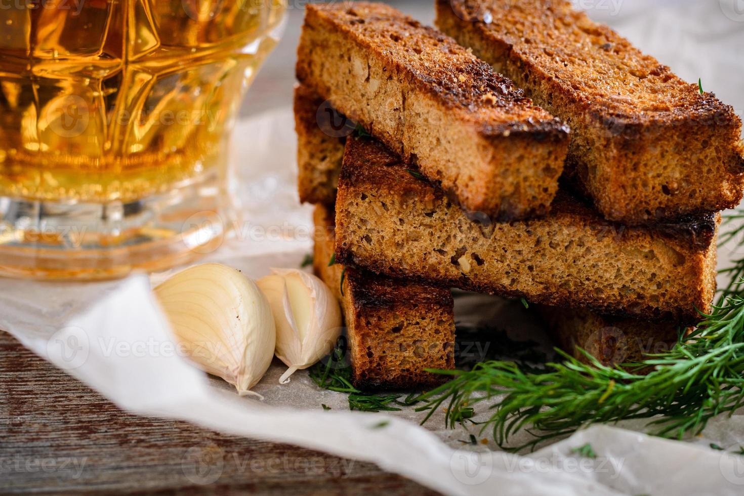 Rye croutons and light beer in a glass mug on a wooden table photo