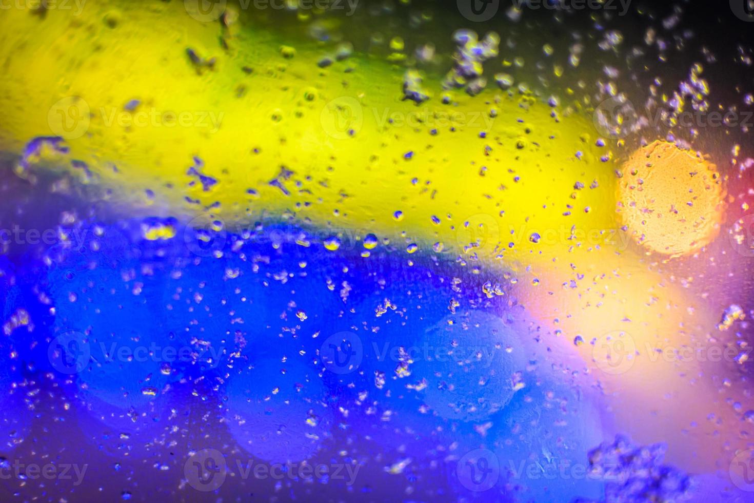 textura de color amarillo y azul, gotas de agua borrosas y puntos de luz en el cristal foto