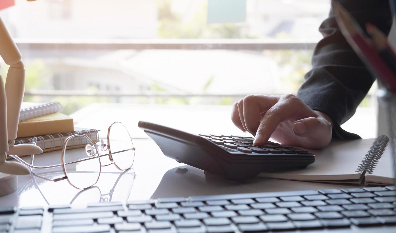 Manos de la empresaria con calculadora y costo en la oficina y análisis de datos financieros contando con escritorio de madera foto