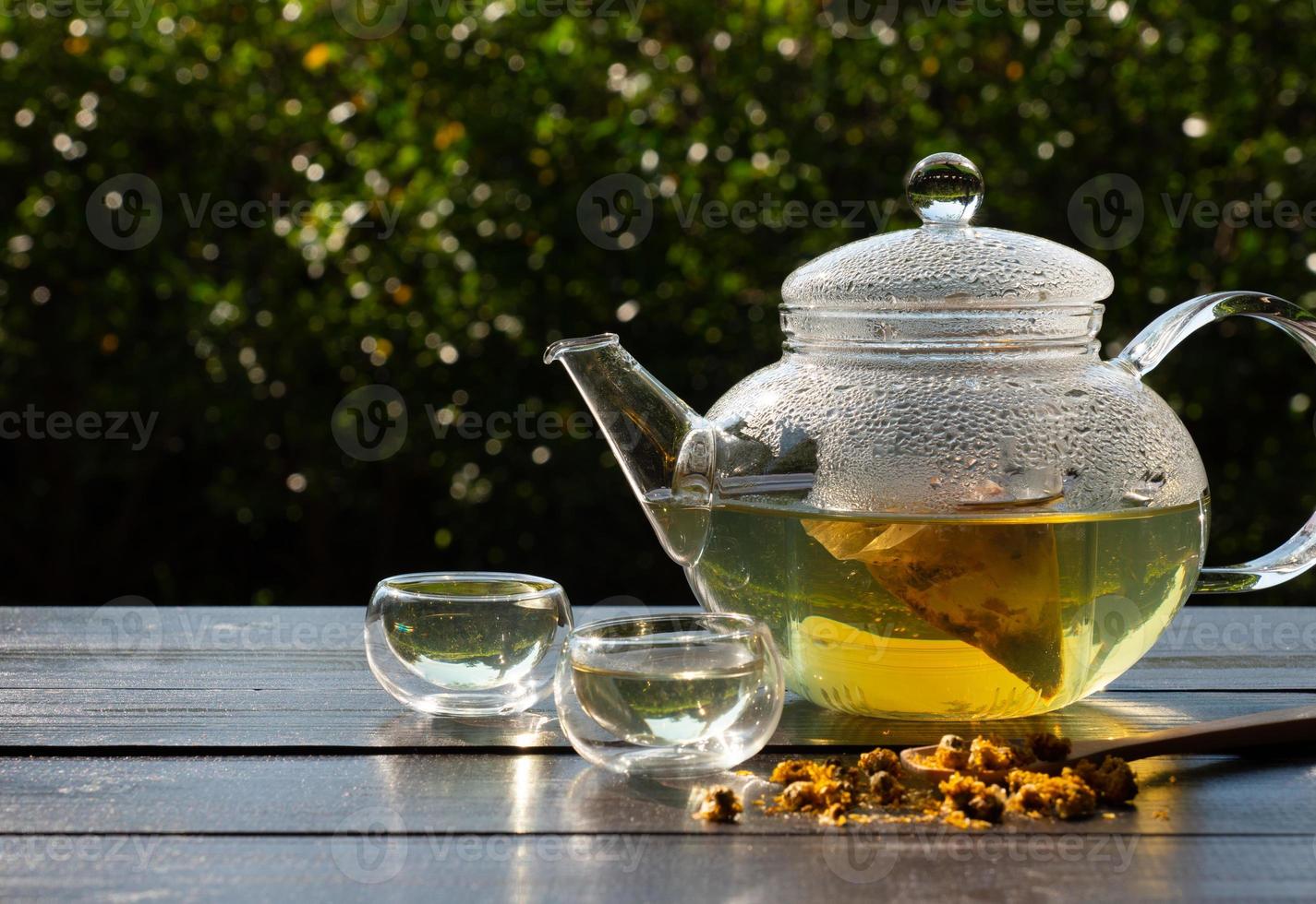 picture of people pouring hot water into clear glass kettle to make Chrysanthemum tea in afternoon in garden photo