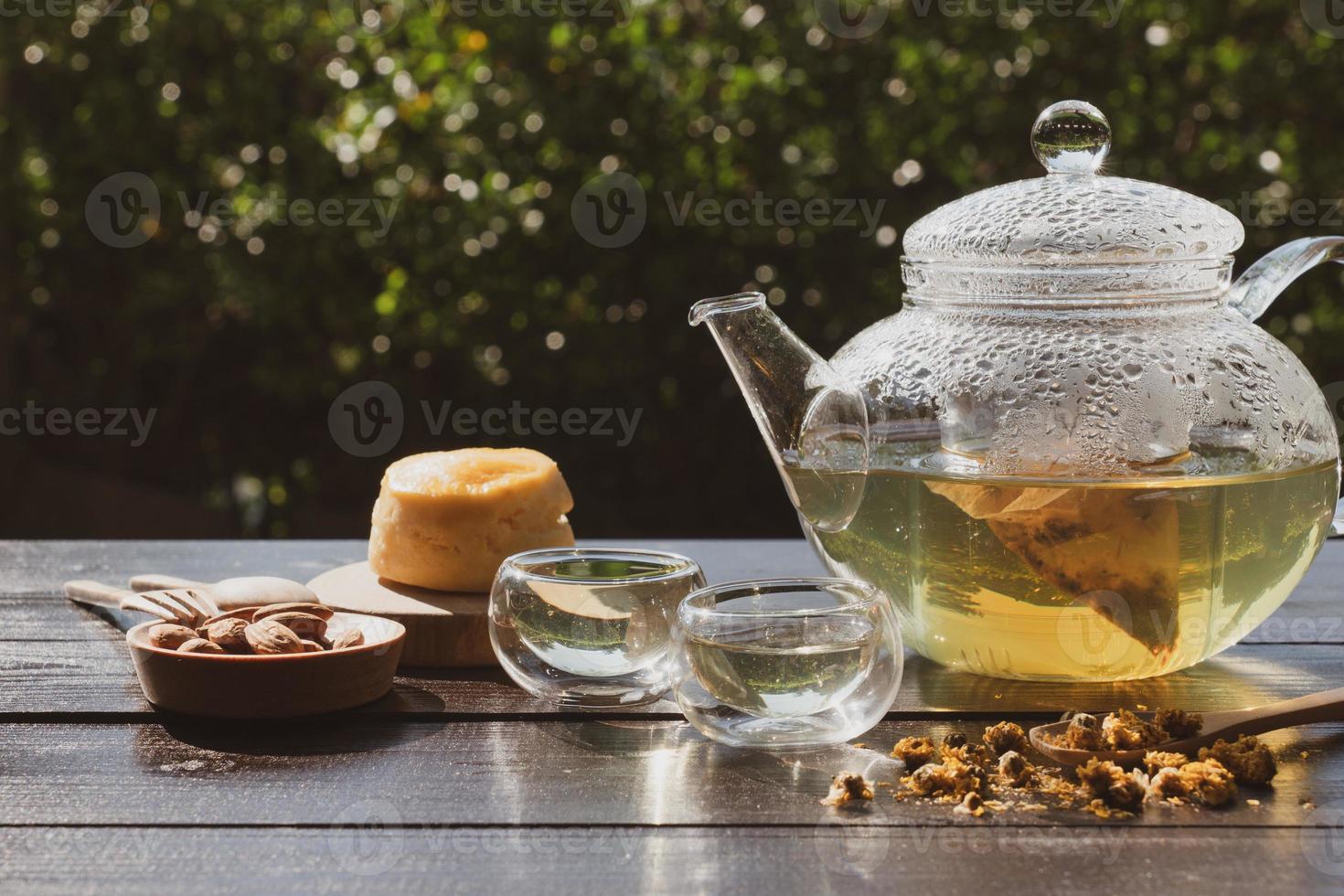 english afternoon earl grey tea in glass kettle with bakery on wooden table in garden photo