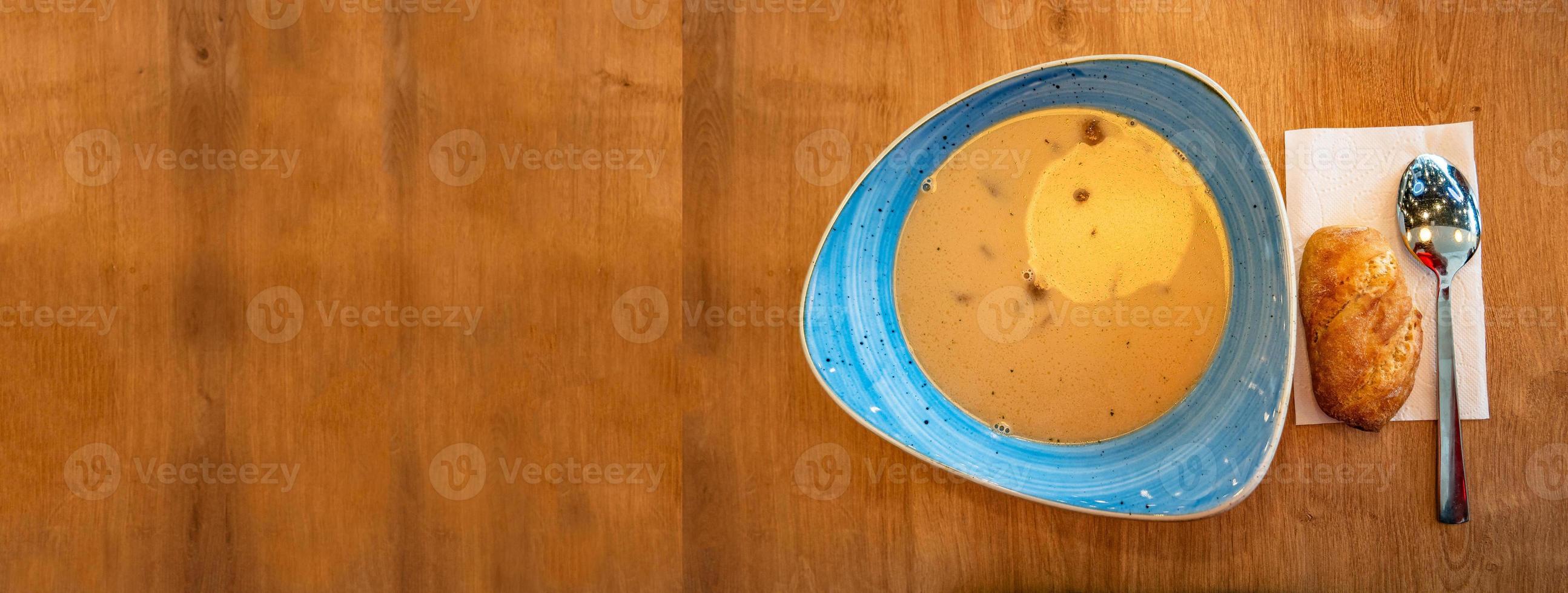 Banner with delicious and appetizing soup with vegetables, tomato and meat, homemade bread, served at wooden table with spoon at smooth old wood background for copy space text, details, closeup. photo