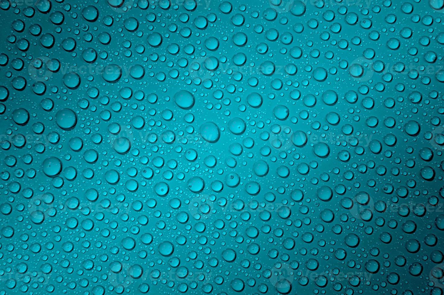 Wet with water drops dark turquoise background with gradient illumination at two corners, macro photo