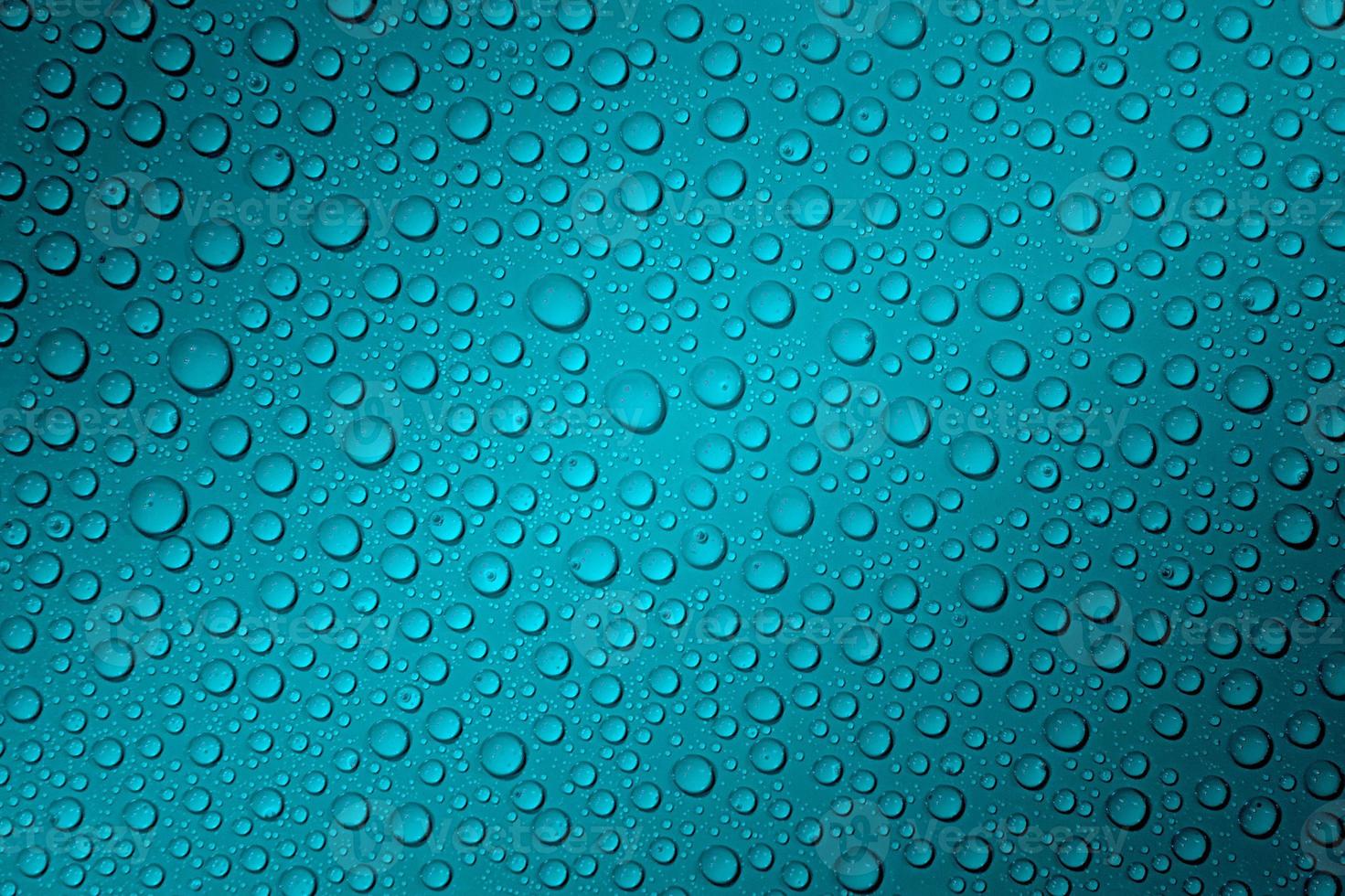 Wet with water drops dark turquoise background with gradient illumination at two corners, macro photo