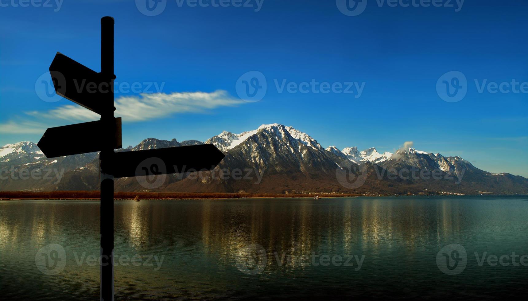 Banner with mountains with black hiking trailhead post showing directions with copy space and blue sky sunset background. Concept of travel, hiking and mountaineering. photo