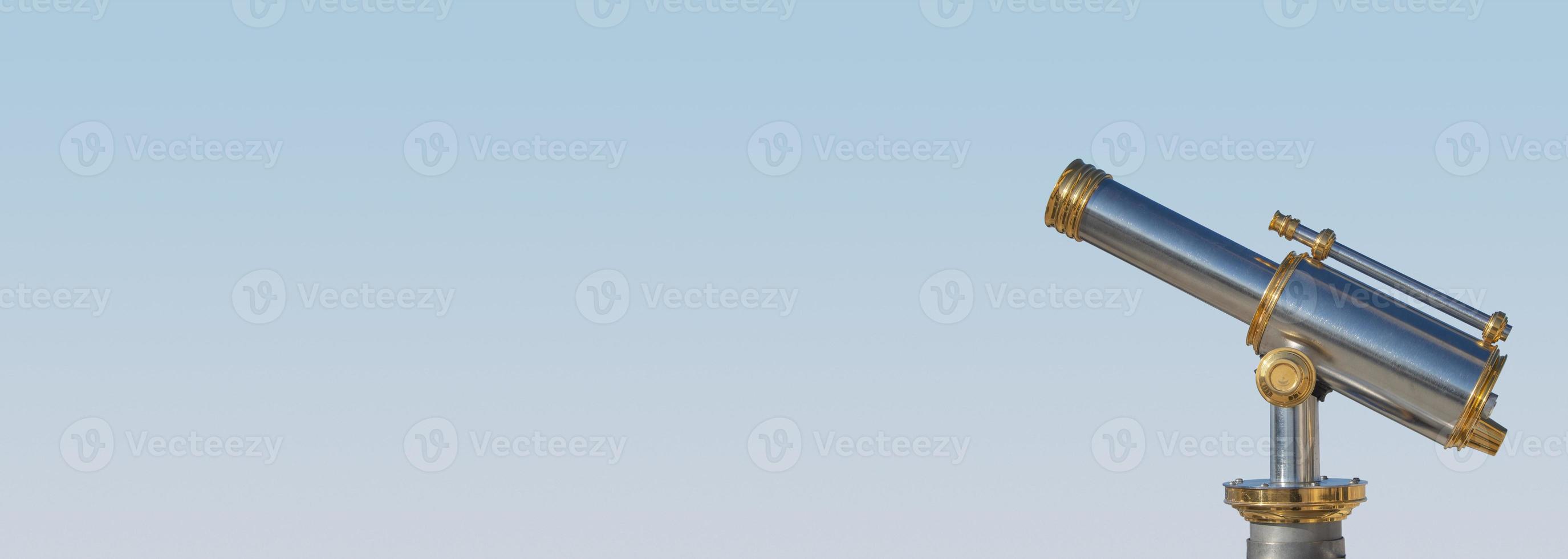 Banner with an old antique golden telescope at light blue sky background with copy space for text, details, closeup. Concept exploration, investigation and travel. photo