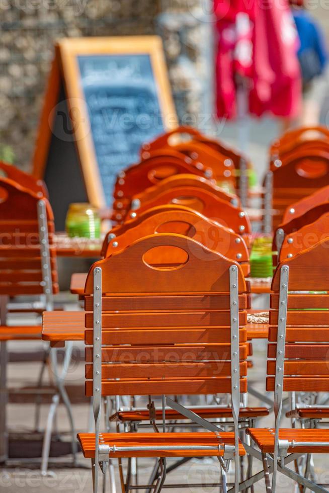Empty red wood chairs and tables and price board in blur background at a lonely restaurant at the historical downtown in Magdeburg, Germany. photo