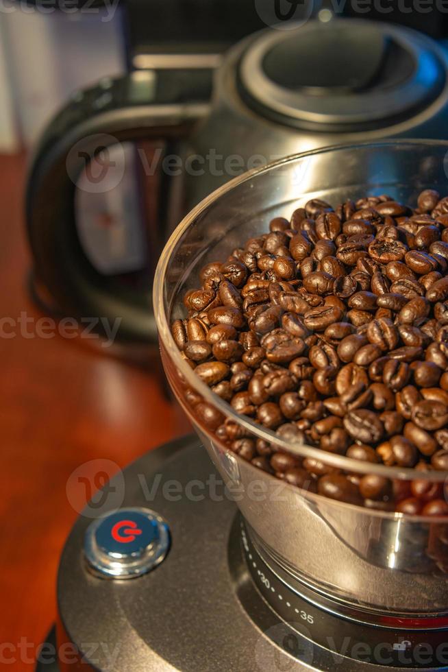 Molinillo de café con botón de inicio rojo, lleno de granos de café frescos, primer plano, detalles foto