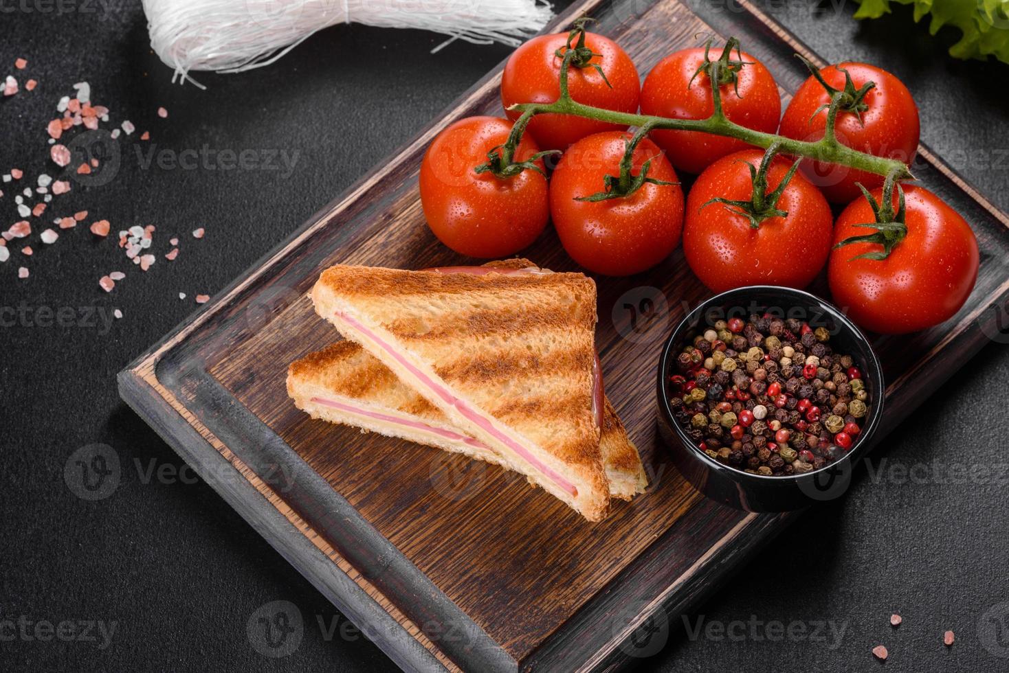 Sandwich with ham, cheese, tomatoes, lettuce, and toasted bread photo