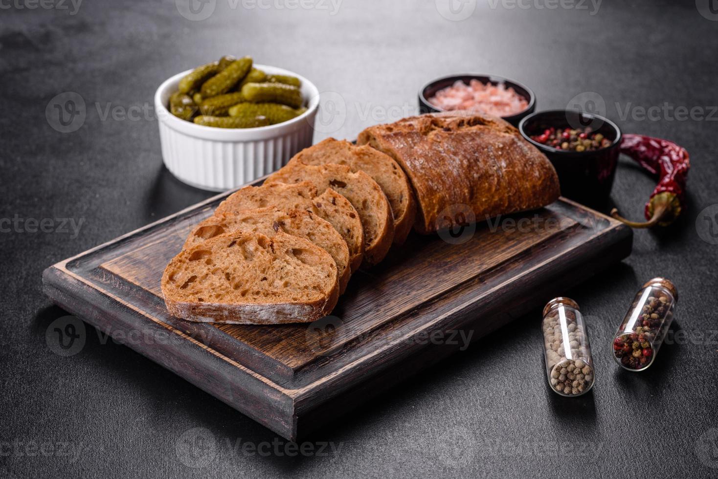 Delicioso pan negro fresco en rodajas con rodajas sobre un fondo de hormigón oscuro foto