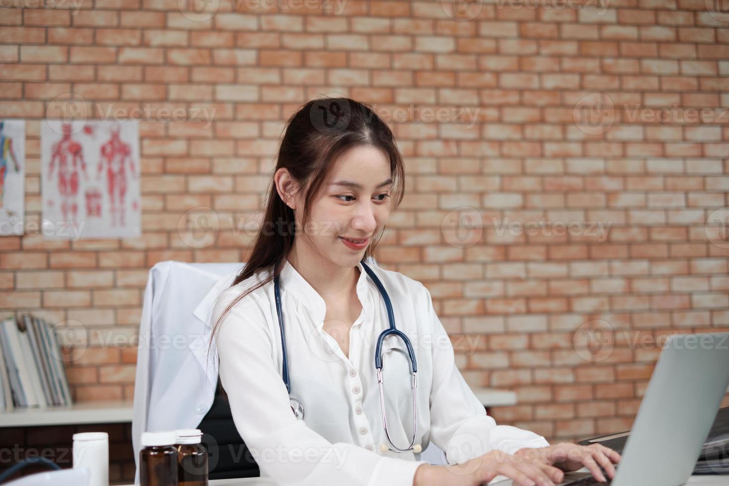 Portrait of beautiful female doctor of Asian ethnicity in white shirt with stethoscope, smiling and looking at the camera in hospital's clinic. One person who has expertise in professional treatment. photo