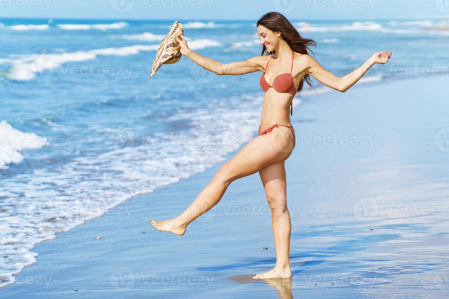 mujer en traje de baño y sombrero para el sol, disfrutando de la playa en sus vacaciones. foto