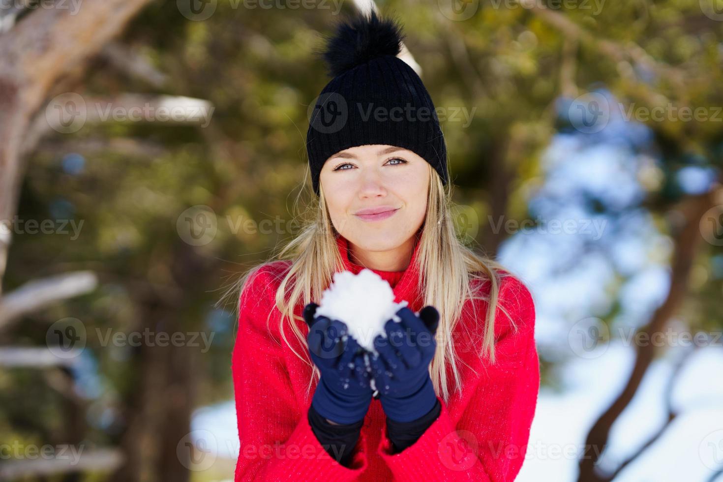 Mujer rubia soplando una bola de nieve en invierno, en sierra nevada, granada, españa. foto