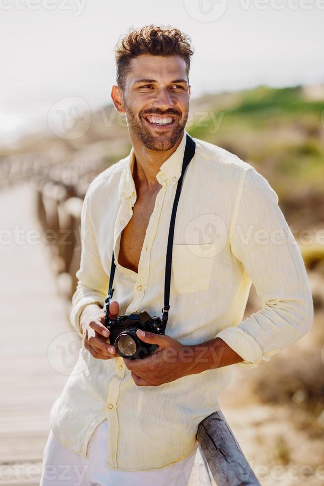 hombre sonriente fotografiando en una zona costera. foto