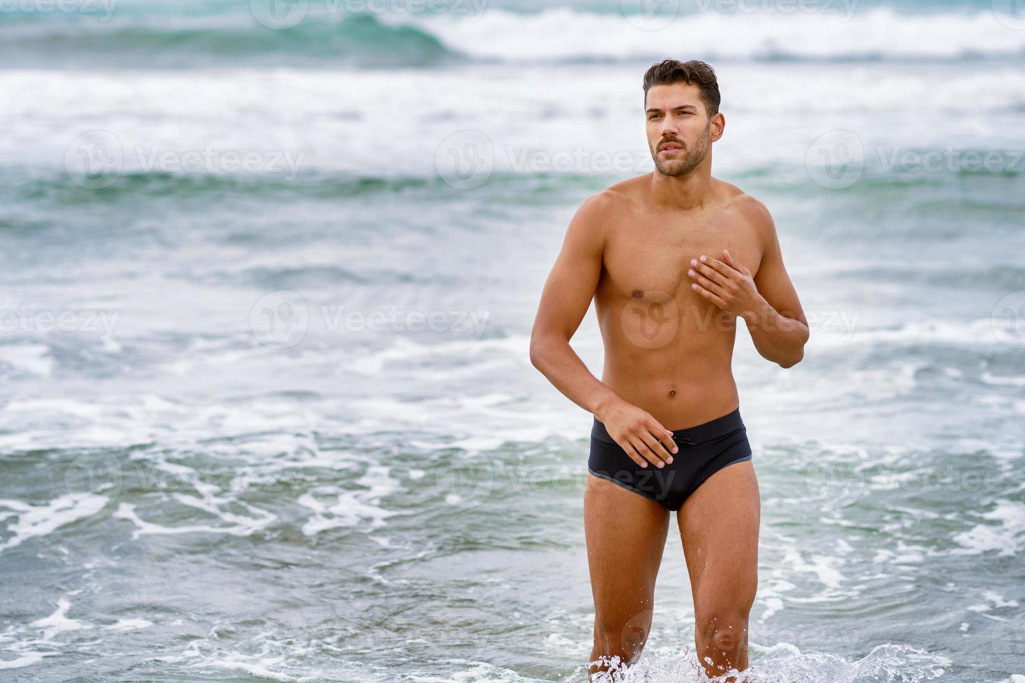 guapo, musculoso, hombre, bañarse en la playa foto