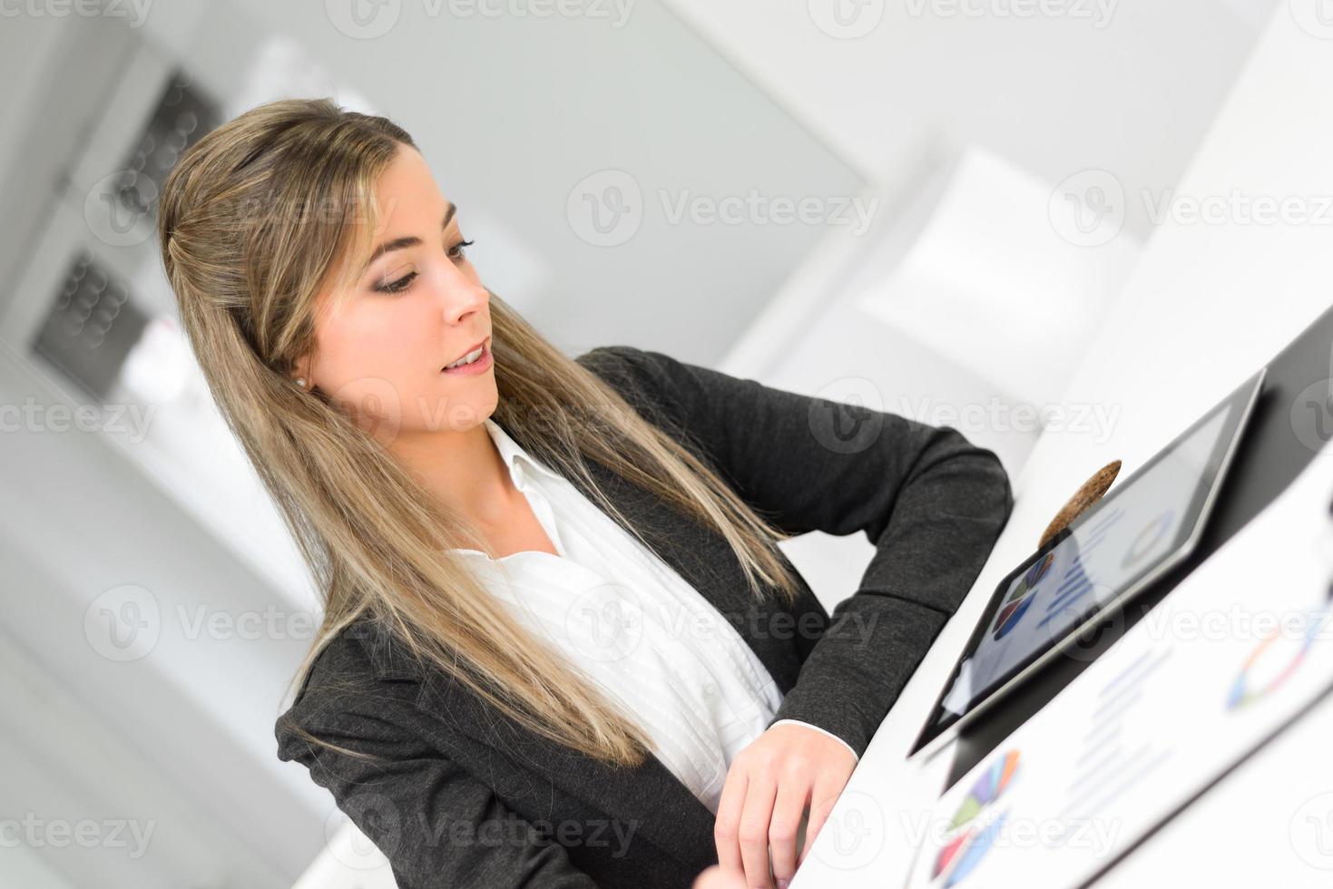 Joven y bella mujer de negocios con tablet PC en la oficina foto