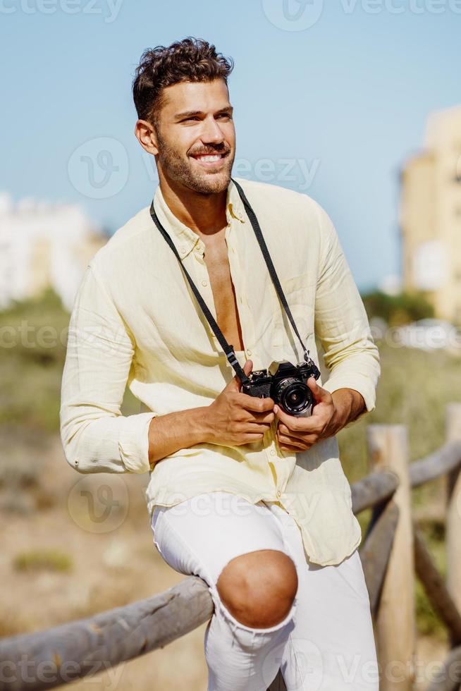 hombre sonriente fotografiando en una zona costera. foto