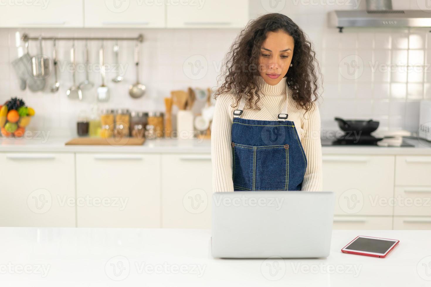 Mujer latina buscando receta para cocinar en la cocina foto