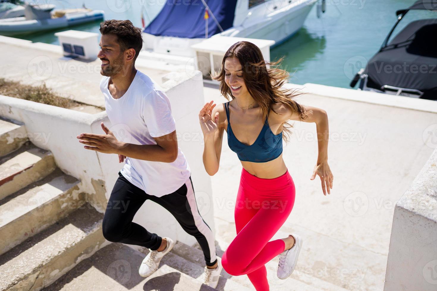 Athletic couple training hard by running up stairs together outdoors. photo