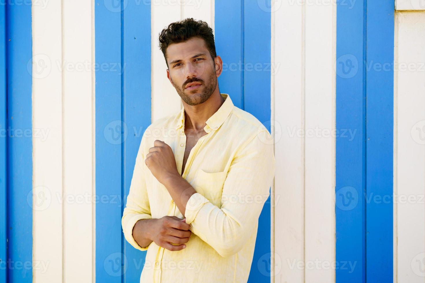 Young man, fashion model, posing in front of a beach booth. photo
