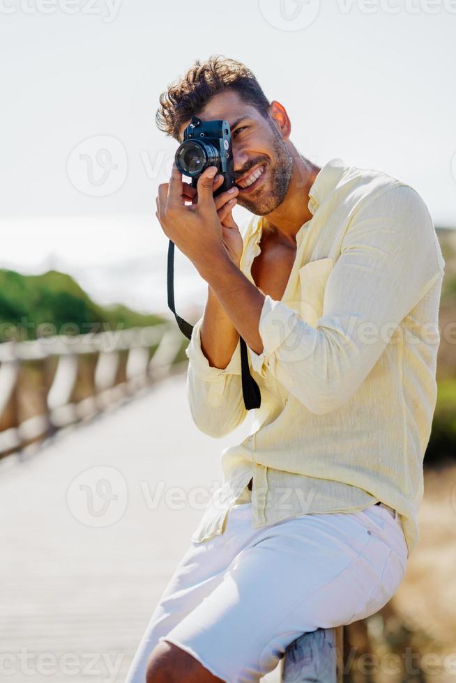 guapo fotografiando en una zona costera. foto