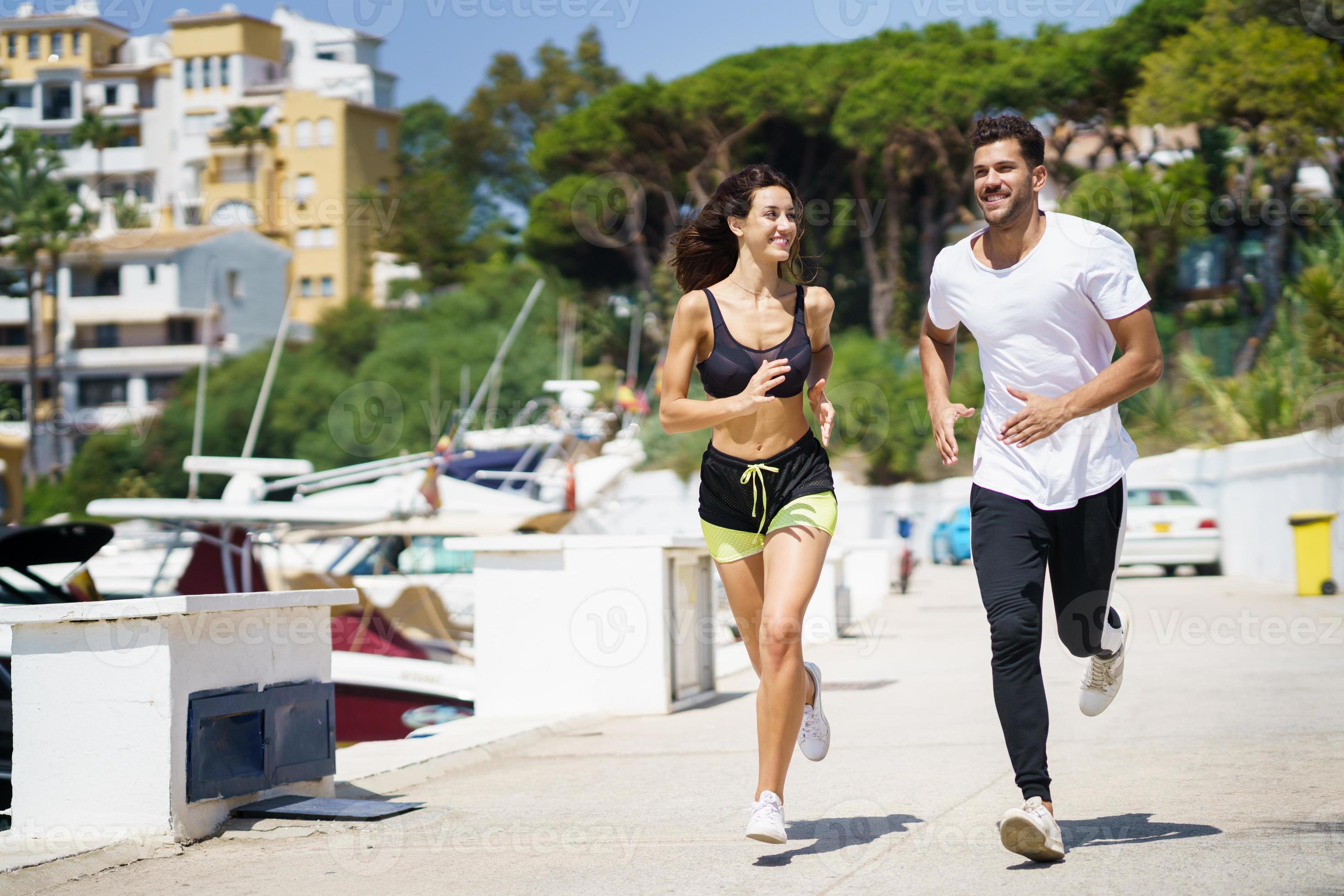 Young couple training together running near the boats in a harbour photo