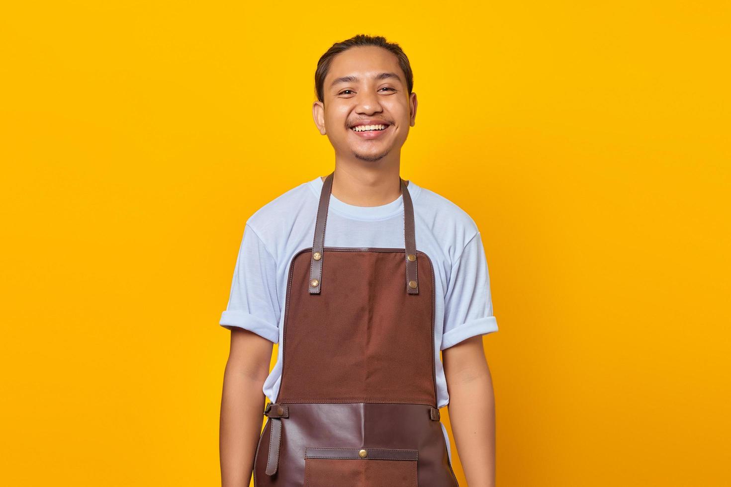 Portrait of cheerful positive man smiling expressing positive emotions on face isolated on yellow background photo