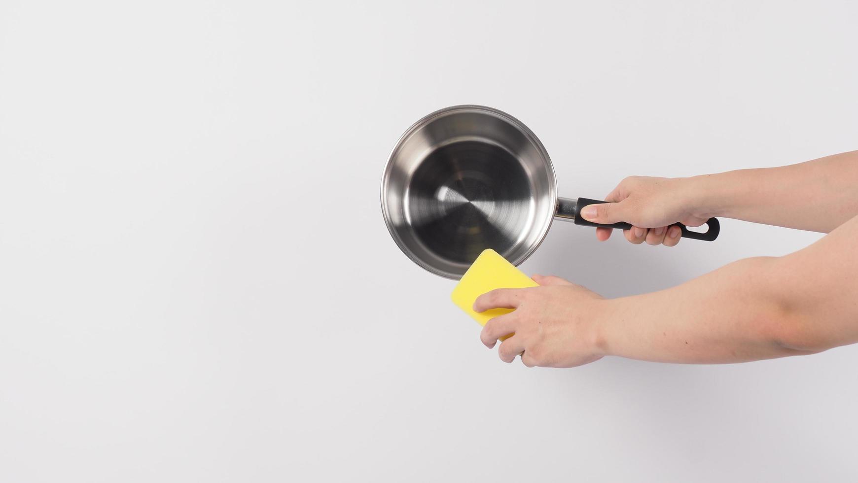 Pot cleaning. Man hand on white background cleaning the non stick pot photo