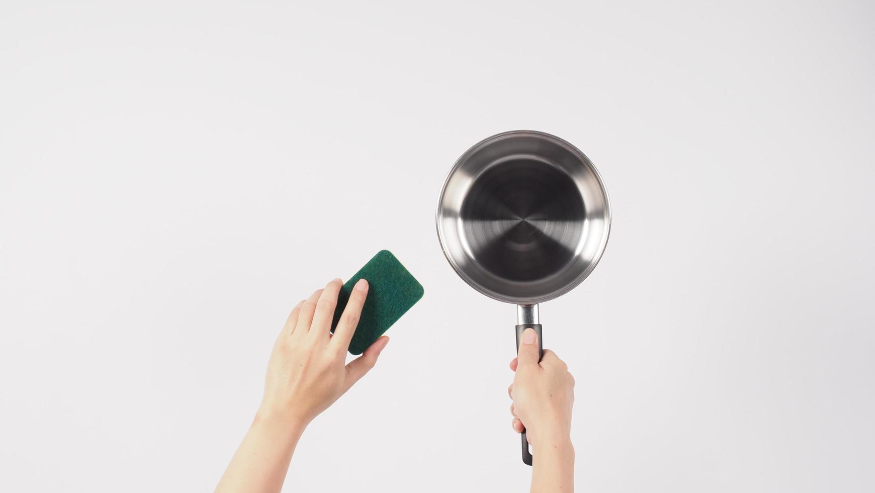 Pot cleaning. Man hand on white background cleaning the non stick pot photo